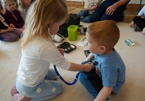 dziewczynka bada stetoskopem kolegę