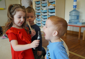 dziewczynka ogląda gardło kolegi