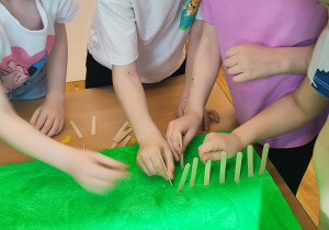 Dzieci tworzą płot z patyczków