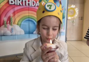 Dziewczynka dmucha świeczkę urodzinową