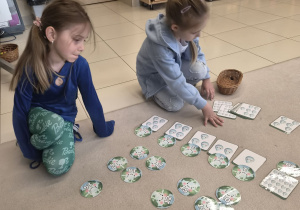 Dziewczynki układają na dywanie karty z liczbami i kroplami wody