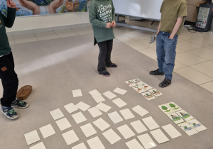 Dzieci grają w ekologiczne memory na dywanie.