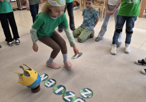 Dziewczynka w opasce układa literę do napisu Dzień Ziemi