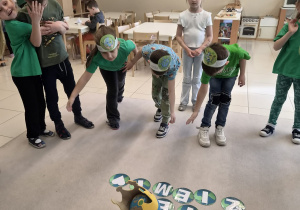 Grupa dzieci kłania się ziemi w koronie.