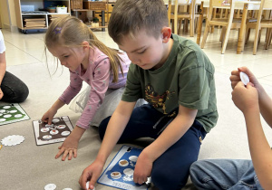Chłopiec i dziewczynka dopasowują obrazki różnych odpadów do odpowiednich plansz do segregacji