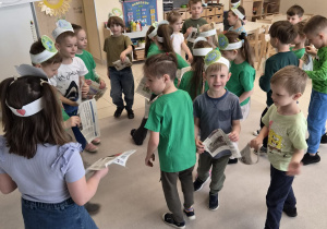 Starszaki tańczą w kole, trzymając kawałki gazet.