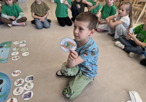 Chłopiec pokazuje planszę z ekologicznym symbolem.