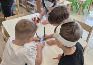 Dzieci wspólnie kolorują plakat na Dzień Ziemi, siedząc przy stoliku.