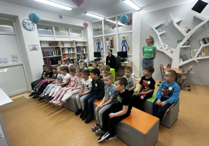 Dzieci uważnie słuchają pań w bibliotece szkolnej