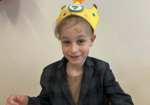 Chłopiec w koronie siedzi przy stoliku