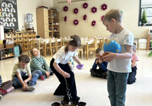 Chłopiec trzyma globus a dziewczynka rozkłada koraliki