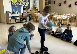 Chłopiec trzyma globus a dziewczynka rozkłada koraliki