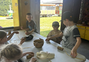 dzieci oplątują sznurkiem domek dla pszczół