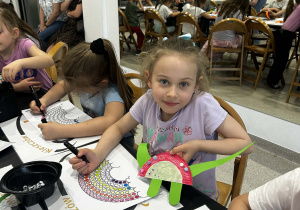 Dziewczynka pozuje z wykonanym przez siebie dinozaurem