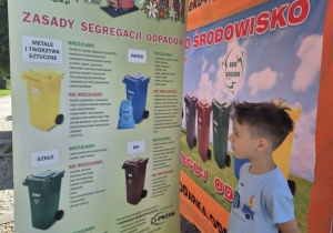 chłopiec czyta informacje na temat segregacji śmieci