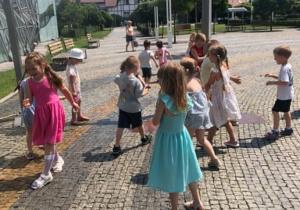 dzieci chłodzą sie pod zraszaczem