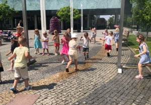 dzieci chłodzą sie pod zraszaczem