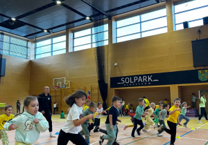 Dzieci biegają po hali sportowej