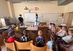 dzieci siedzą i patrzą na eksperymet z ultrafioletem