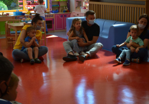 Dzieci siedzą z rodzicami na podłodze