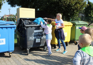 dzieci wrzucają śmieci do pojemników