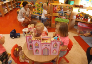 Dziewczynki bawią się domkiem dla lalek 