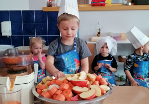 Dziecko wrzuca jabłko i marchewkę do sokowirówki