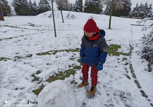 chłopiec toczy kulę śniegu