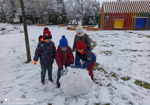 dzieci toczą kulę śniegową