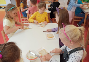 dzieci smarują chleb masłem czosnkowo-ziołowym