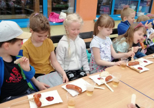 dzieci jedzą kiełbaski