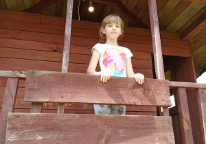 dziewczynka stoi na balkonie domku