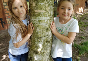 dziewczynki przytulają się do drzewa