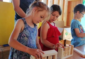 dzieci składają drewniane elementy