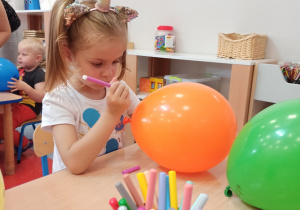 dziewczynka maluje kropki na balonie