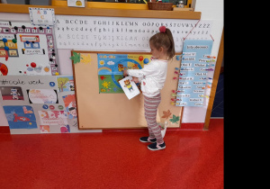 Dziewczynka wskazuje obrazki postaci na plakacie klasowym