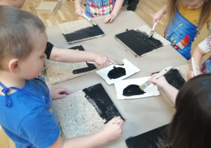 Dzieci maluja czarną farbą