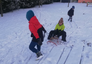 chłopiec ciągnie kolegę sankami