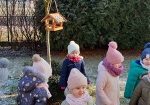 dzieci stoją przed karmnikiem