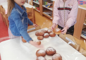 dziewczynki układają pączki na tacy